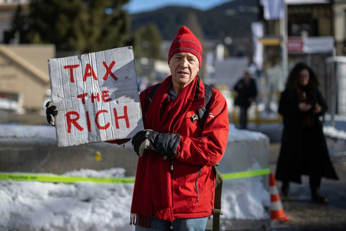 British millionaire Phil White carries protest sign "Tax the rich" outside the World Economic Forum British millionaire Phil White carries protest sign "Tax the rich" outside the World Economic Forum