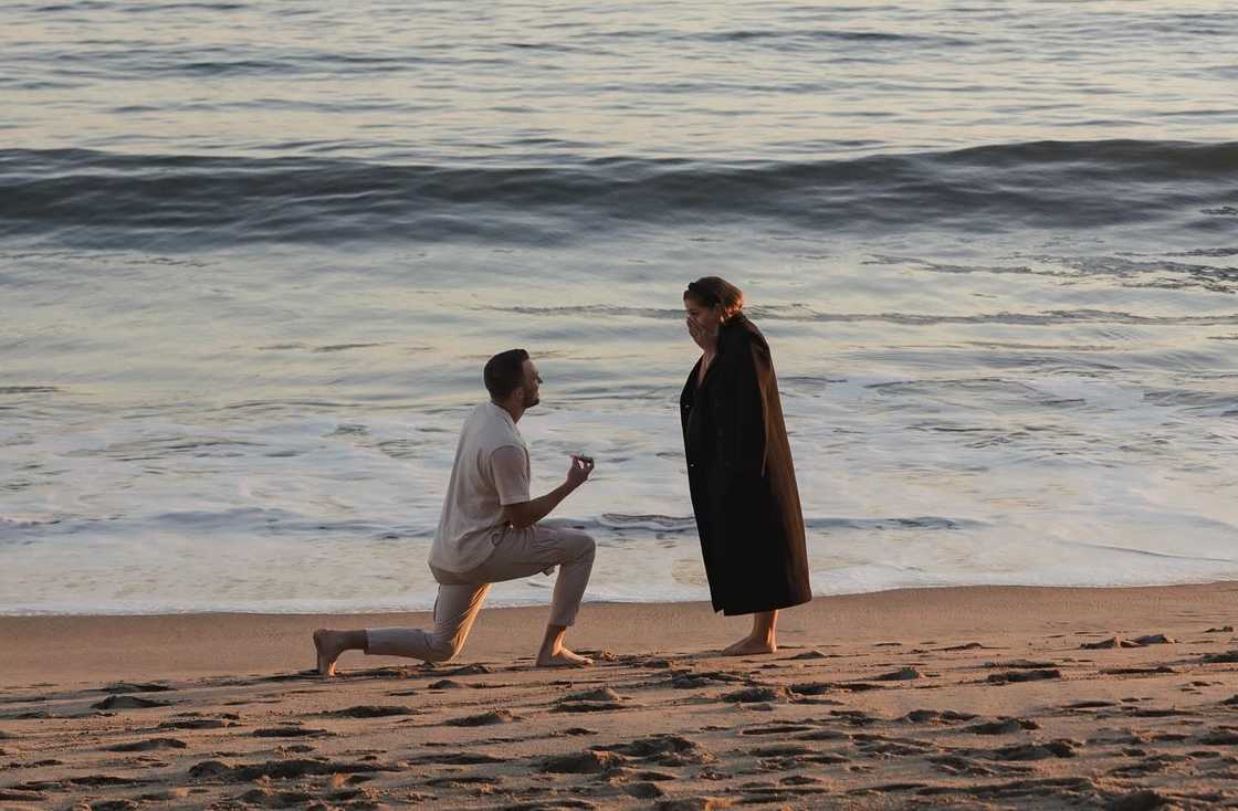 Jake proposes on a sandy beach at sunset, holding a ring box. Jake proposes on a sandy beach at sunset, holding a ring box.