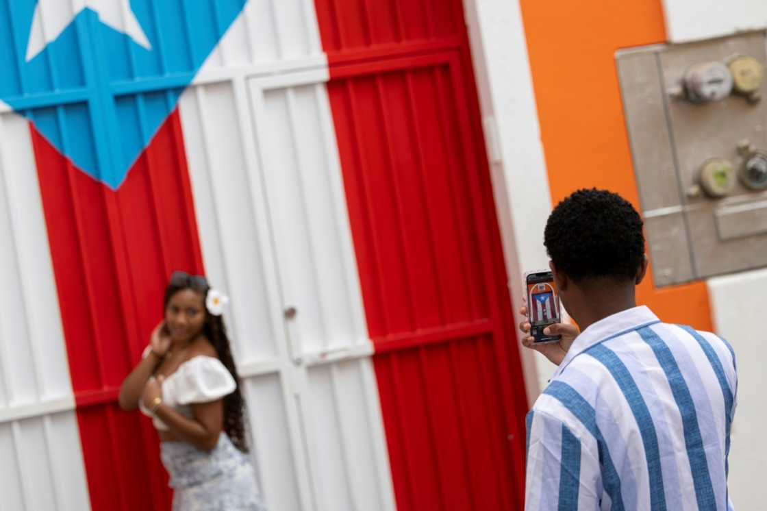 A man photographs a woman in front of a Puerto Rican flag mural in Old San Juan, Puerto Rico on May 13, 2025 A man photographs a woman in front of a Puerto Rican flag mural in Old San Juan, Puerto Rico on May 13, 2025