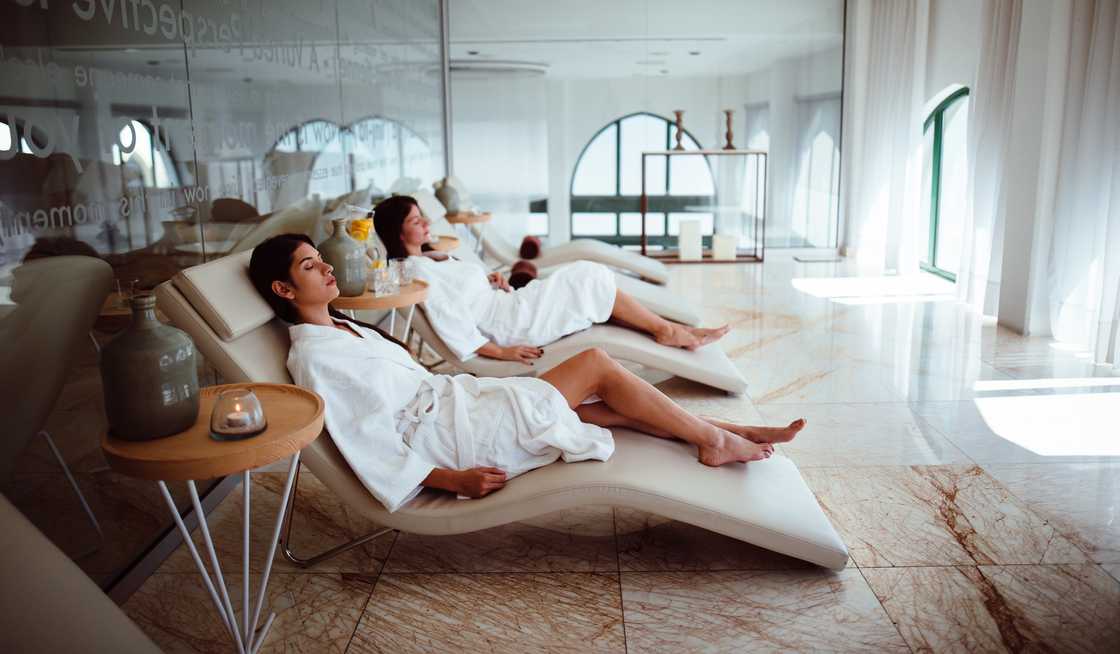 Young women in white robes relaxing at a beauty spa.