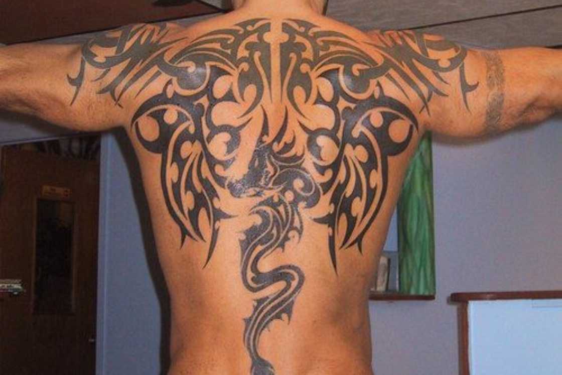 A man has an intricate black back tattoo A man has an intricate black back tattoo