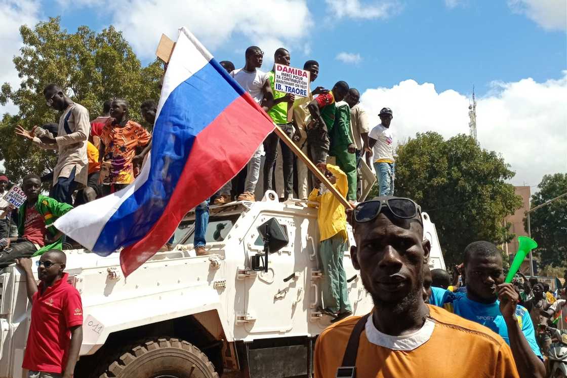 Pro-Moscow: Demonstrators waving a Russian flag stand atop a UN peacekeepers' vehicle in Ouagadougou on Sunday Pro-Moscow: Demonstrators waving a Russian flag stand atop a UN peacekeepers' vehicle in Ouagadougou on Sunday