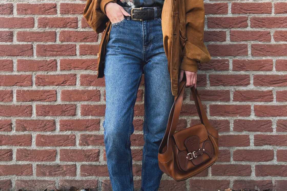 A person is rocking a blue jeans with a brown jacket and bag A person is rocking a blue jeans with a brown jacket and bag