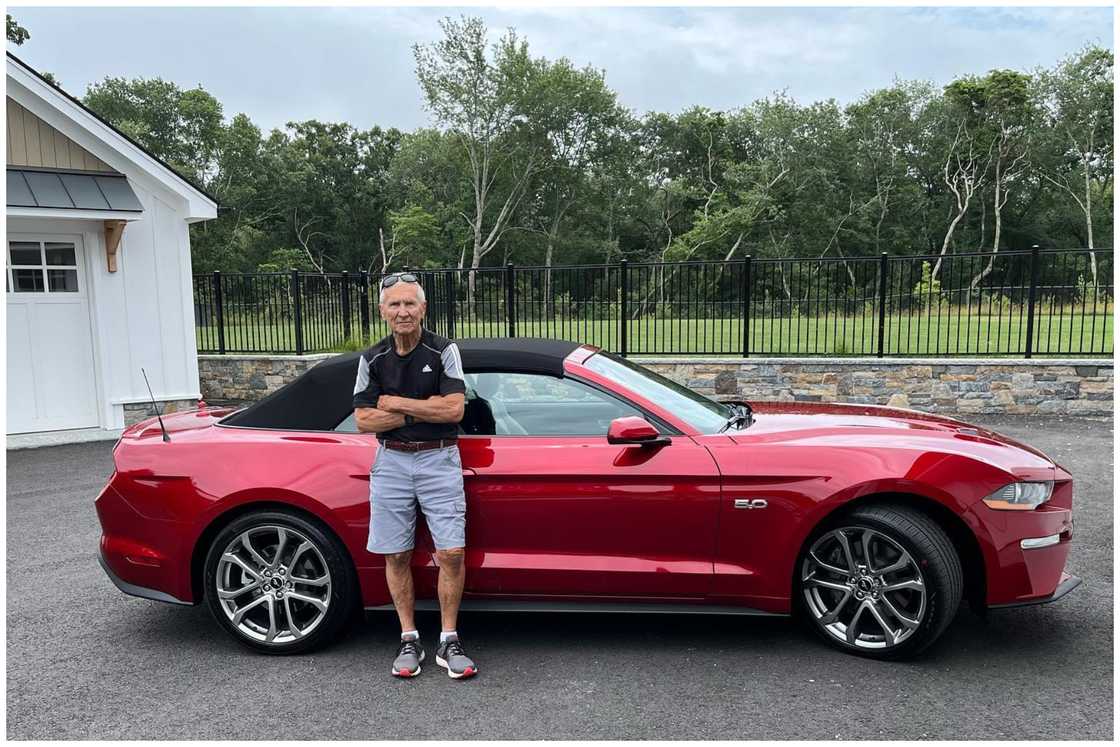 Jeff Sweenor poses next to a red car
