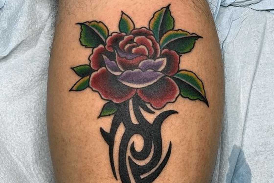 A multi-coloured tribal rose leg tattoo A multi-coloured tribal rose leg tattoo