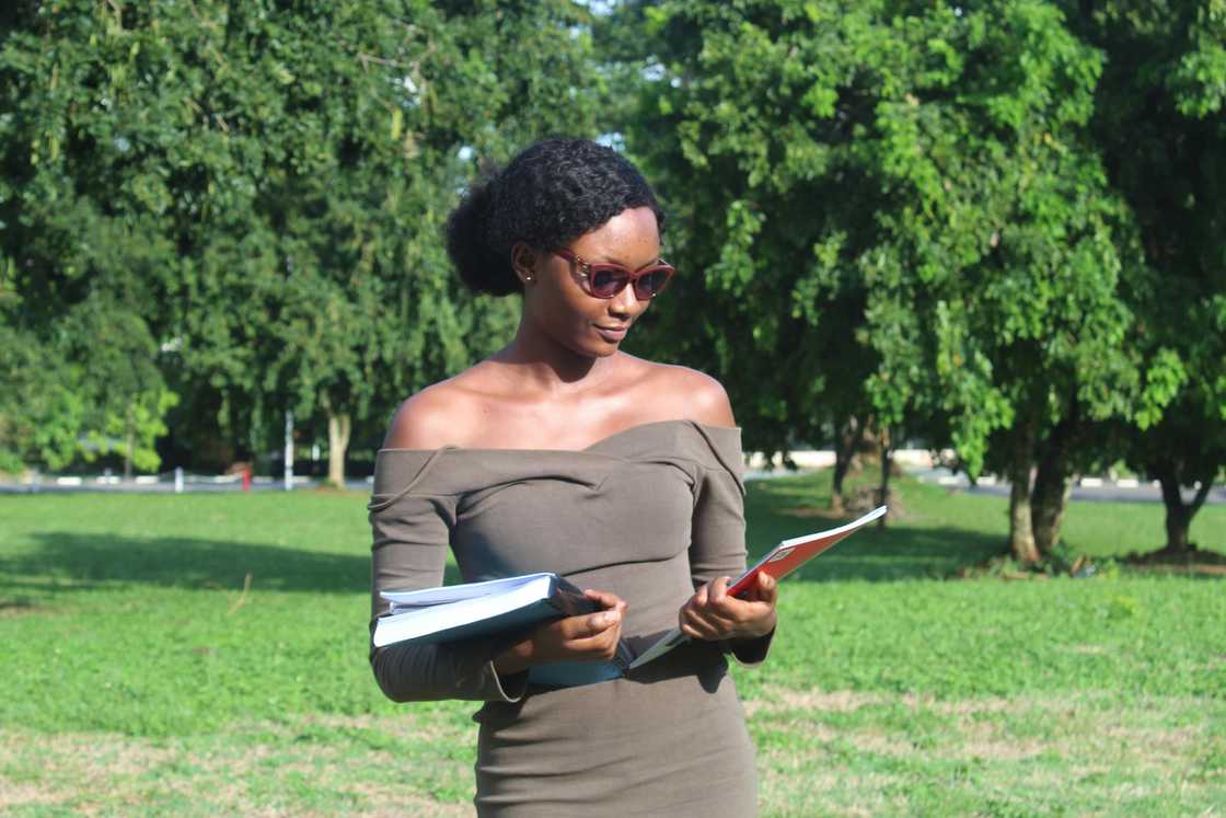 A young woman in a brown off-shoulder dress is holding books A young woman in a brown off-shoulder dress is holding books
