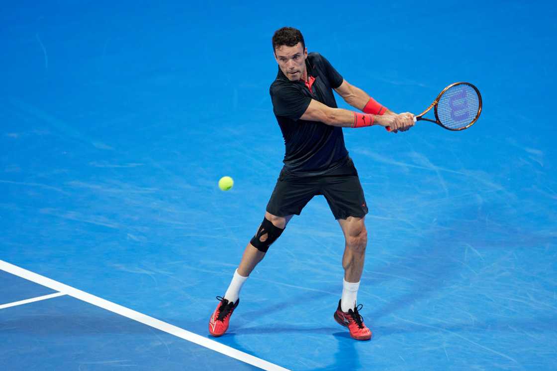 A tennis player swinging a racket at a ball during a game of tennis.