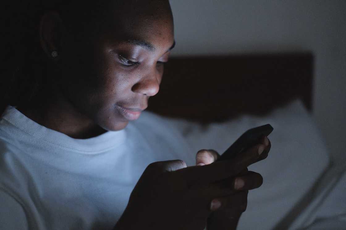 A woman looks at her phone screen in low light. A woman looks at her phone screen in low light.
