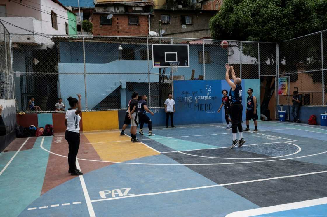 A young basketball referee trainee (L) observes a game between two local youth teams supported by the Caracas Mi Convive NGO, at Santa Eduviges neighbourhood in Caracas in August 20, 2022