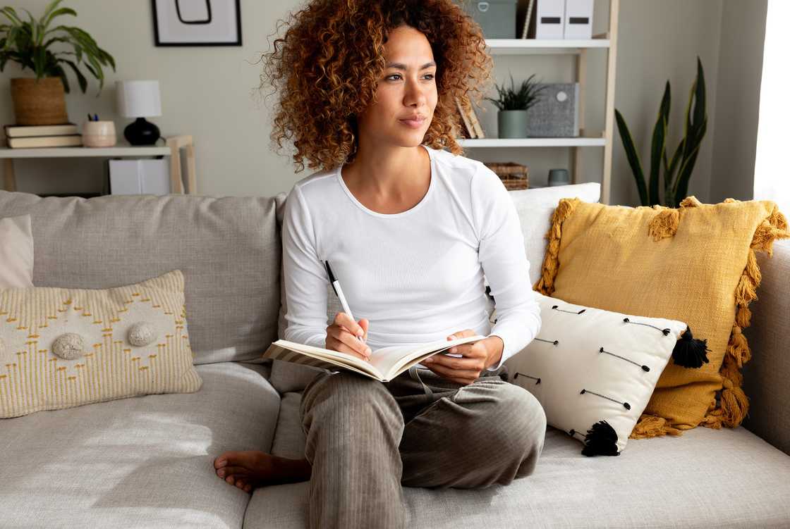 Person with curly hair writes in a notebook. Person with curly hair writes in a notebook.