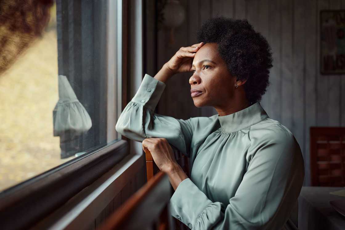 A worried African American woman is looking through the window A worried African American woman is looking through the window