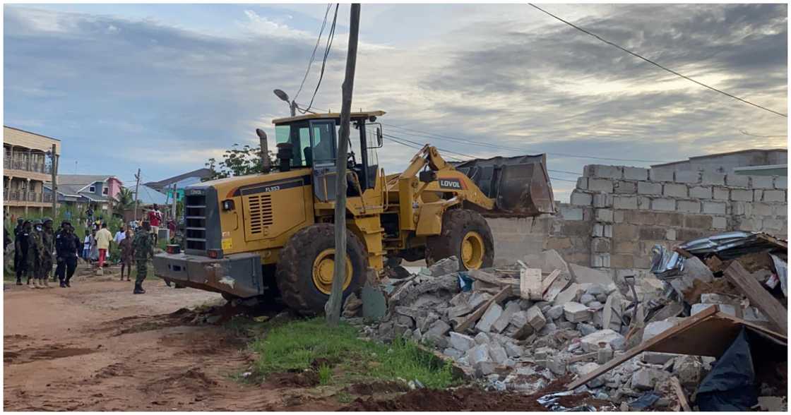 A Caterpillar truck brings down unauthorized buildings on CSIR property