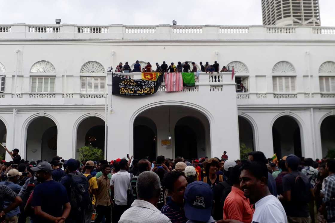 Protesters are seen on the balcony of the presidential palace on Saturday Protesters are seen on the balcony of the presidential palace on Saturday