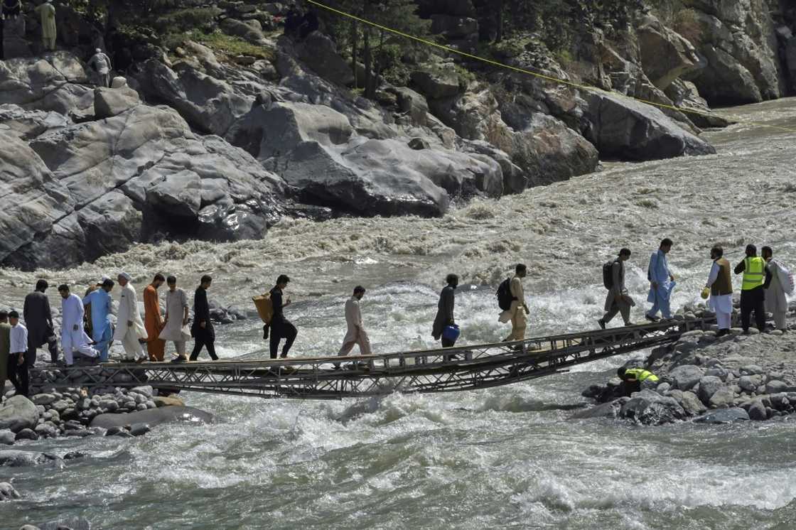 A vehicle bridge across the Swat River was destroyed by a flash flood, and now the only way across is by a rickety makeshift footbridge. A vehicle bridge across the Swat River was destroyed by a flash flood, and now the only way across is by a rickety makeshift footbridge.