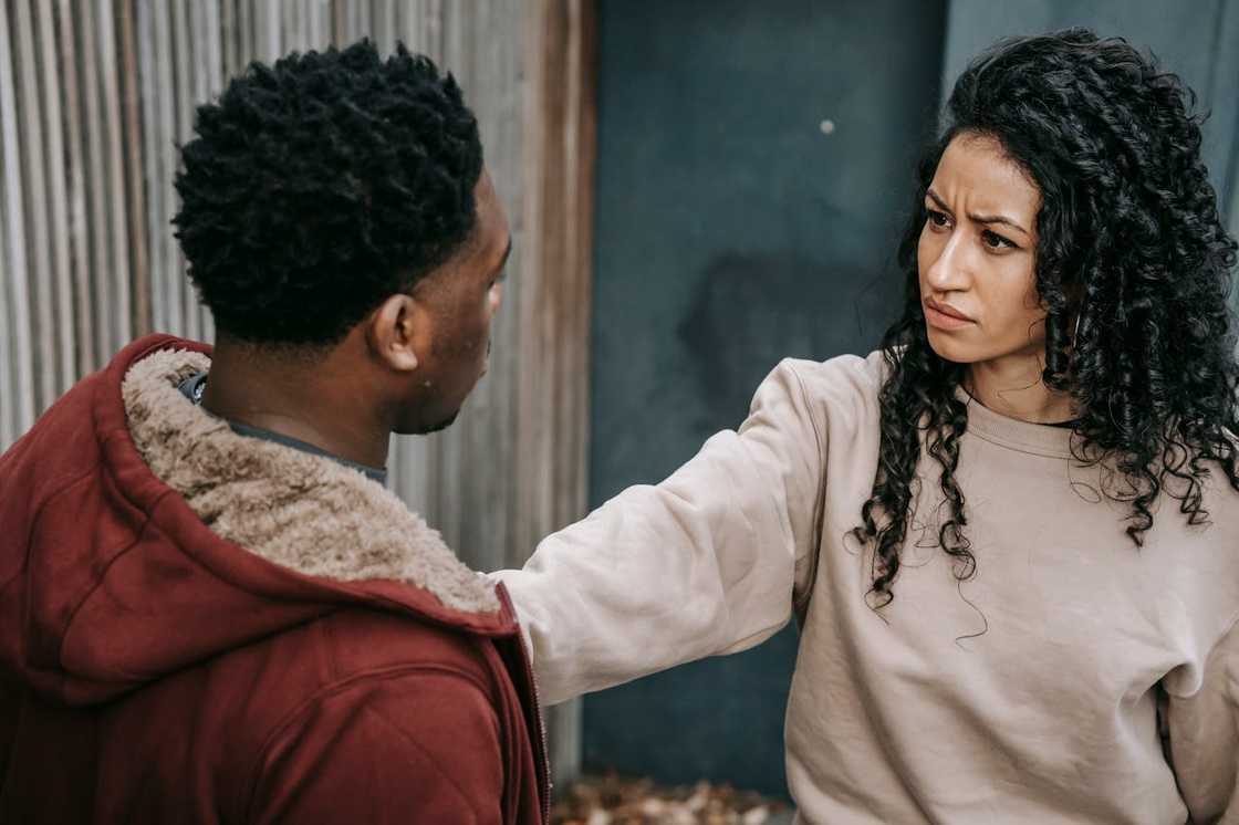 A man confronts a woman with a serious expression.