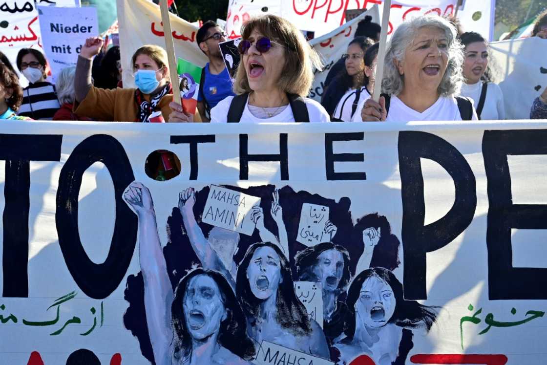 Protesters hold a banner depicting protesters and commemorating Kurdish Iranian Mahsa Amini, who died in Iranian custody