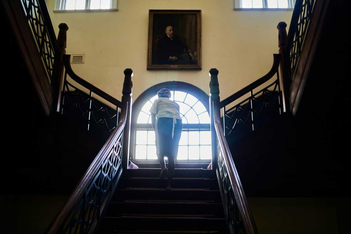 A cleaner works under a portrait of the queen in the Bulawayo Club, a former gentleman's retreat in the Bulawayo, Zimbabwe's second largest city