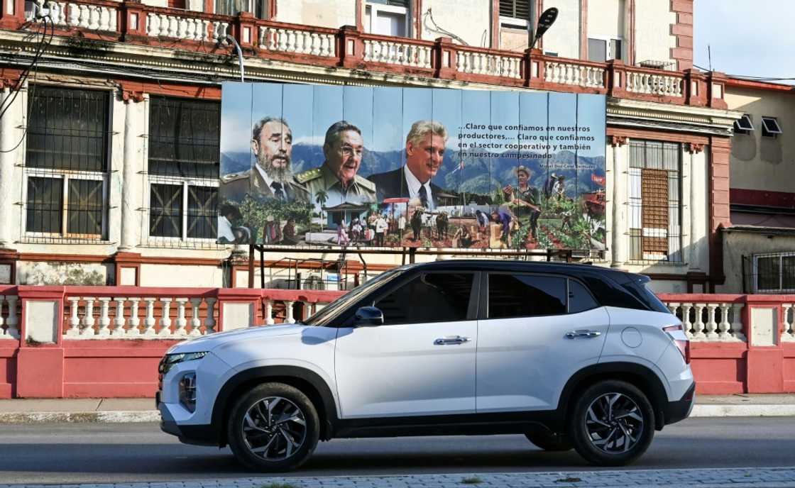 Un SUV circule devant une affiche représentant le chef de la révolution cubaine, Fidel Castro, son frère et ex-dirigeant Raul Castro et le président Miguel Diaz-Canel, à La Havane, le 5 septembre 2024 Un SUV circule devant une affiche représentant le chef de la révolution cubaine, Fidel Castro, son frère et ex-dirigeant Raul Castro et le président Miguel Diaz-Canel, à La Havane, le 5 septembre 2024