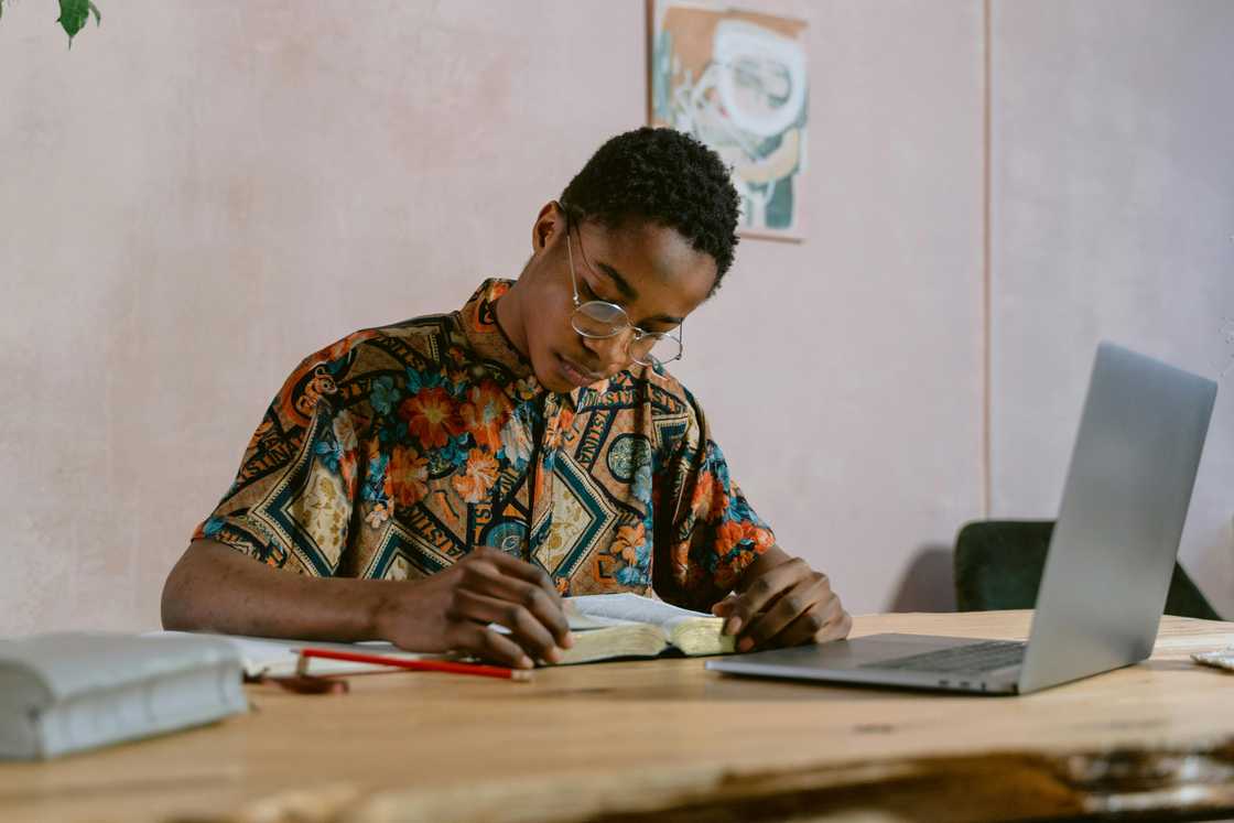 A young man is sitting at the table reading a book