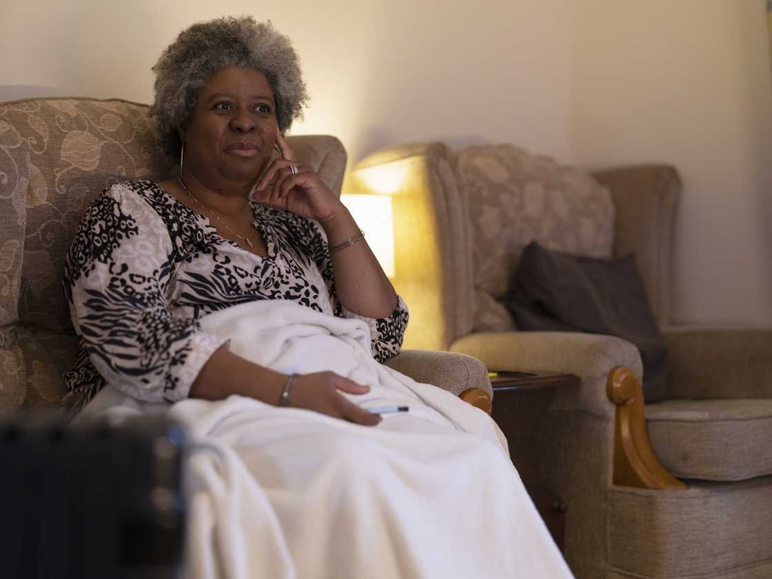 An elderly person relaxing in an armchair with a remote. An elderly person relaxing in an armchair with a remote.
