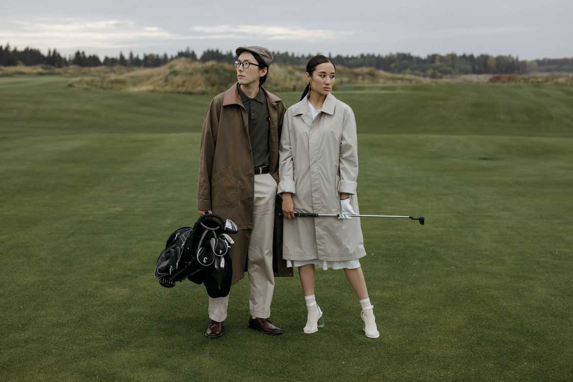 A man and a woman in coats posing at a golf course A man and a woman in coats posing at a golf course