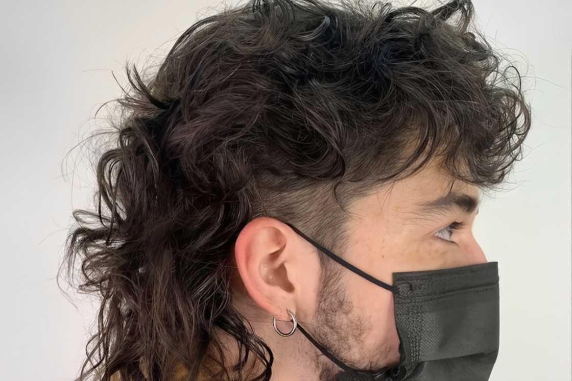 A man wearing a black mask shows off his wavy mullet hairstyle A man wearing a black mask shows off his wavy mullet hairstyle