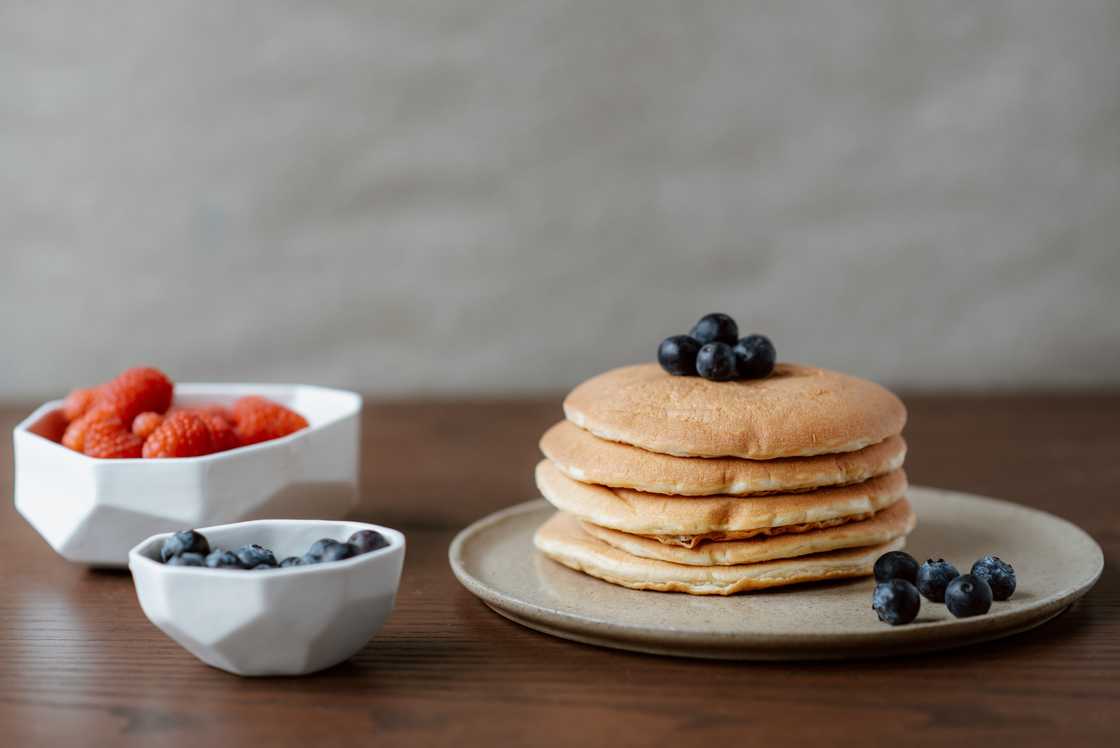 Pancakes on a plate topped with some blueberries and strawberries Pancakes on a plate topped with some blueberries and strawberries