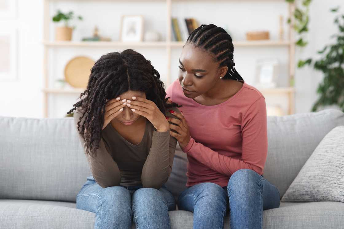 An attentive African American lady is comforting her girlfriend An attentive African American lady is comforting her girlfriend