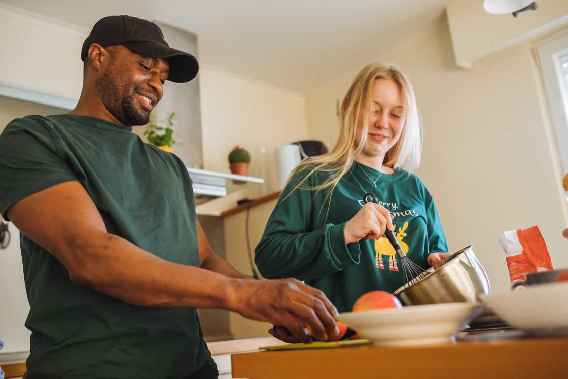 A cheerful dad (L) and his daughter (R) are preparing a sweet pie A cheerful dad (L) and his daughter (R) are preparing a sweet pie