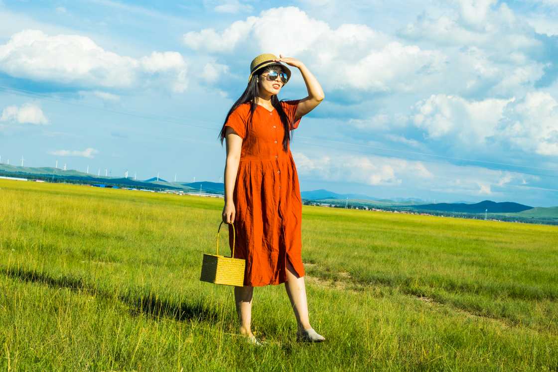 A girl is wearing a red dress in prairie