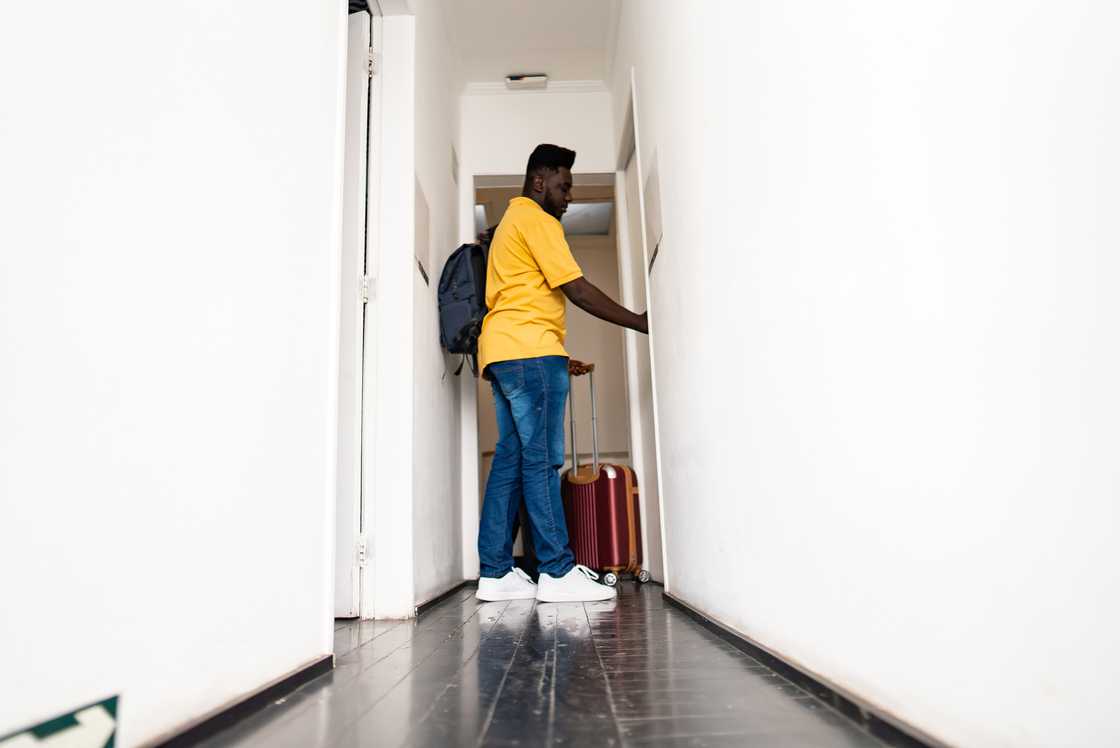 A mid-adult antheral   is opening   the edifice  country   door