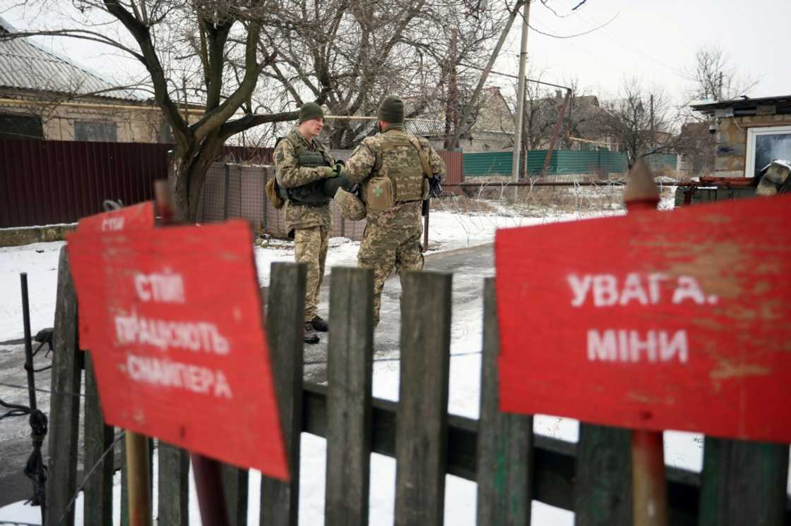 Ukrainian soldiers stand guard near signs reading 'Beware of landmines' Ukrainian soldiers stand guard near signs reading 'Beware of landmines'