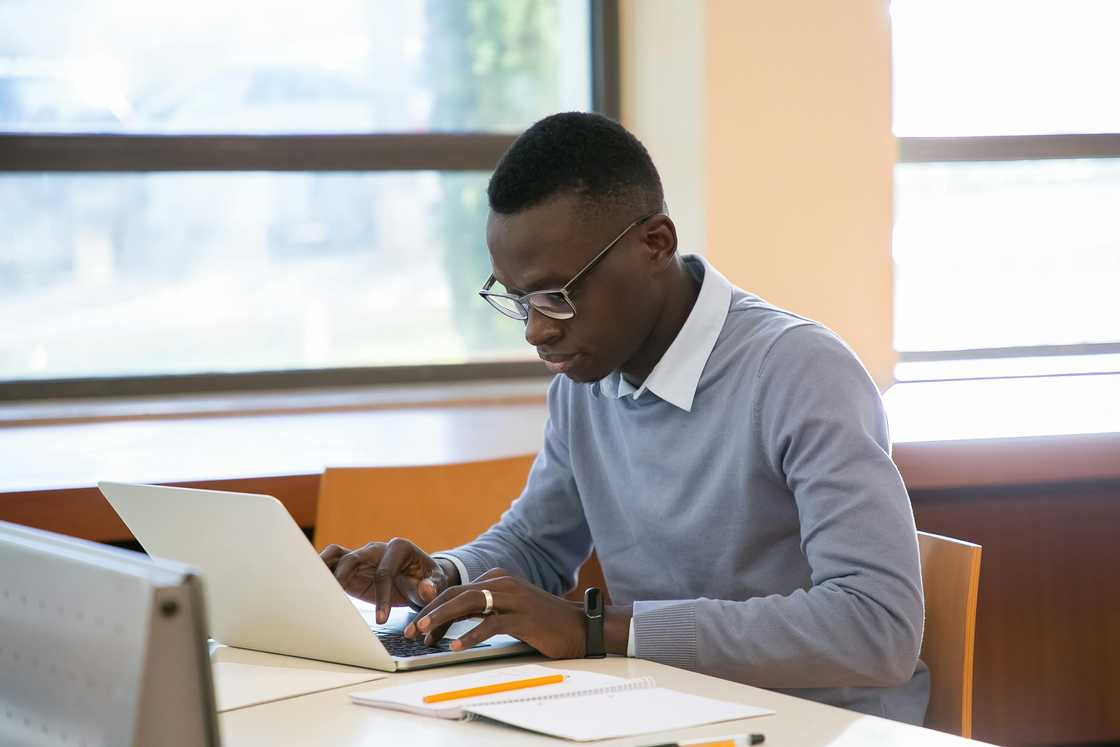 A serious young man is using a laptop