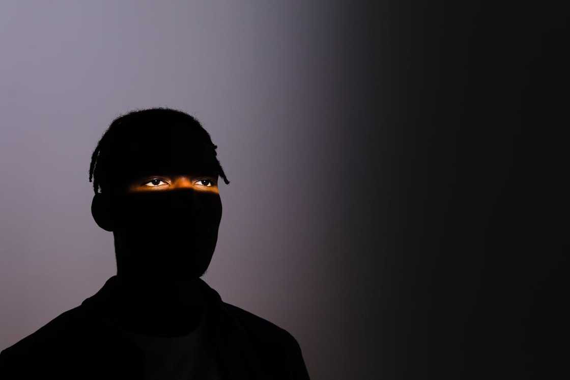 A silhouetted person with eyes lit against a dark background. A silhouetted person with eyes lit against a dark background.