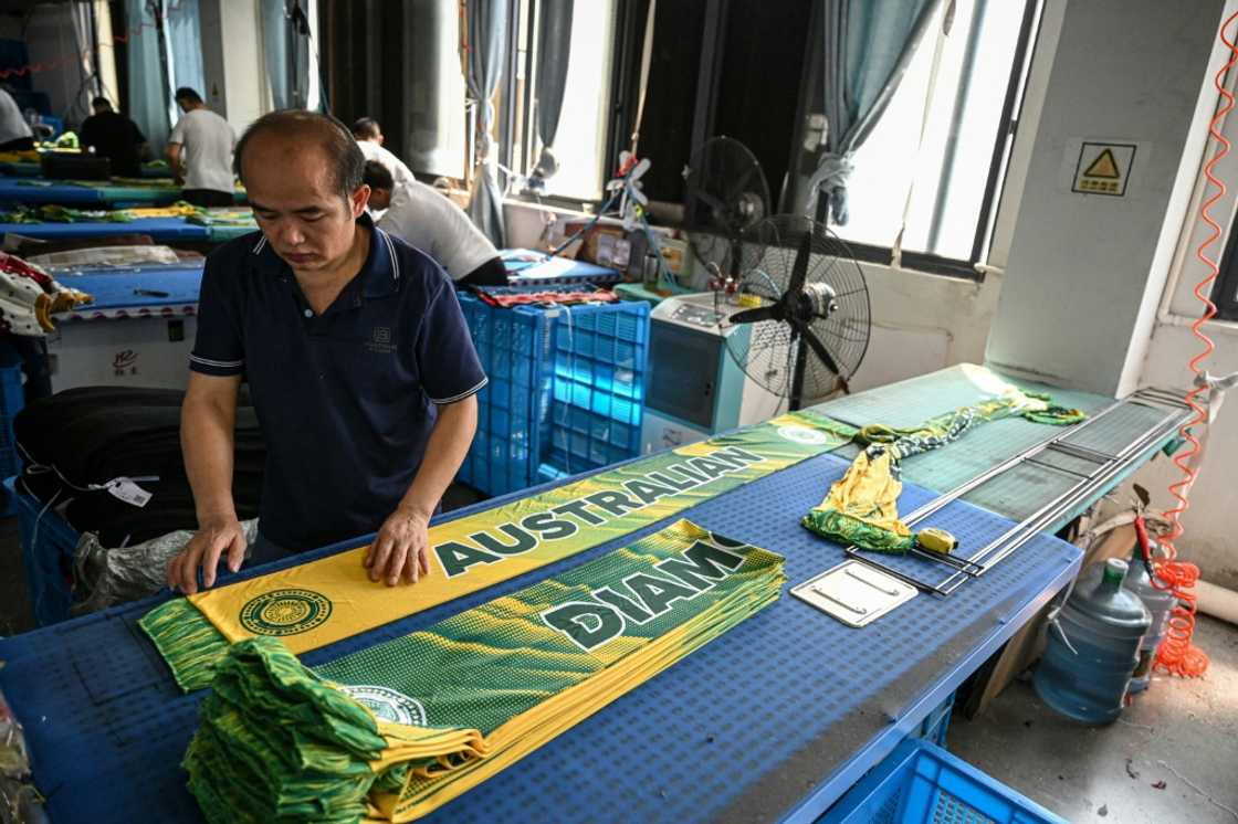 An employee irons scarves at a factory that produces hats and scarves in Yiwu, in eastern China's Zhejiang province on September 18, 2025 An employee irons scarves at a factory that produces hats and scarves in Yiwu, in eastern China's Zhejiang province on September 18, 2025