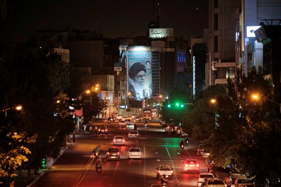 A banner depicting Iran’s Supreme Leader Ayatollah Ali Khamenei is illuminated in downtown Tehran  on June 20, 2021