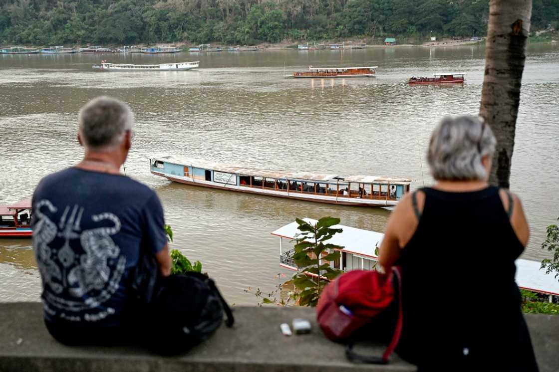 Tourists watch boats cruising on the Mekong river in Luang Prabang Tourists watch boats cruising on the Mekong river in Luang Prabang