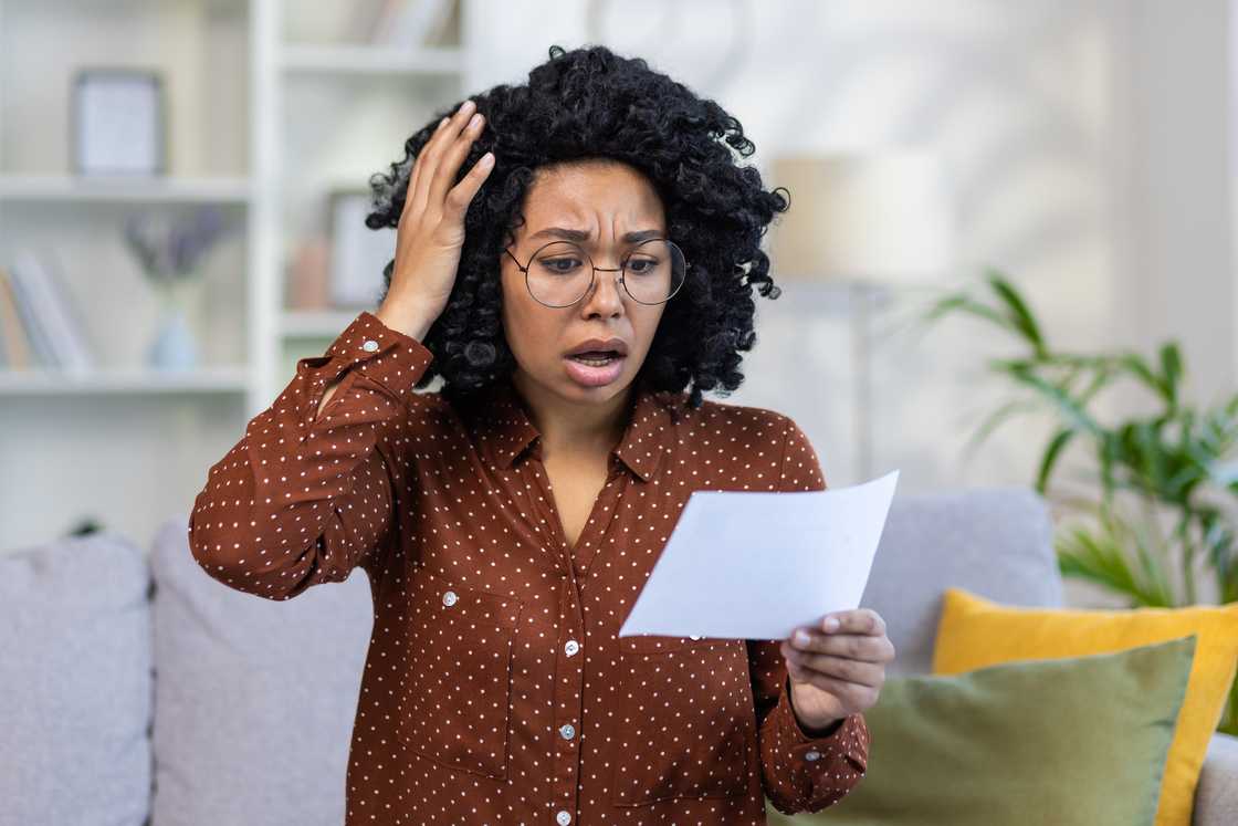 A shocked young woman holding documents