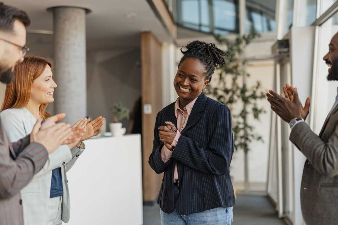 A woman receives a standing ovation from her fellow employees.