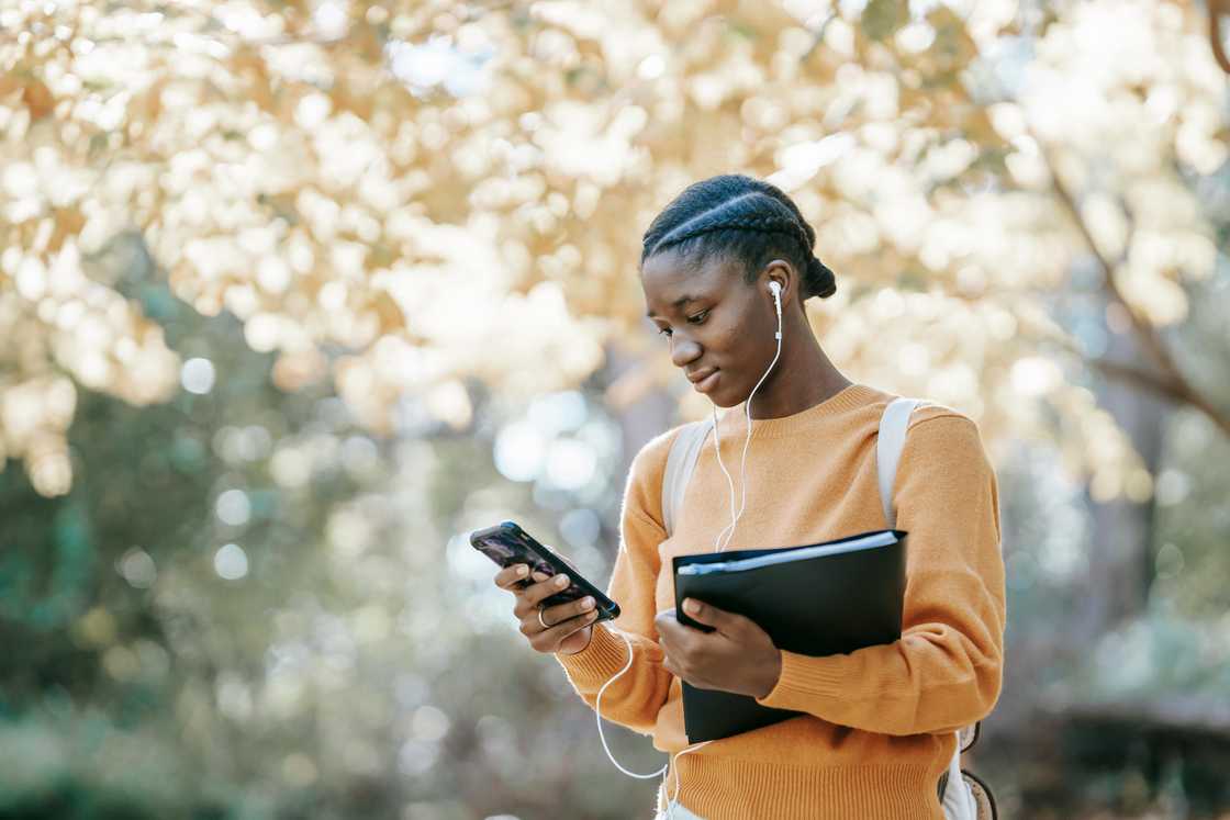 A young female student listening to music using her smartphone A young female student listening to music using her smartphone