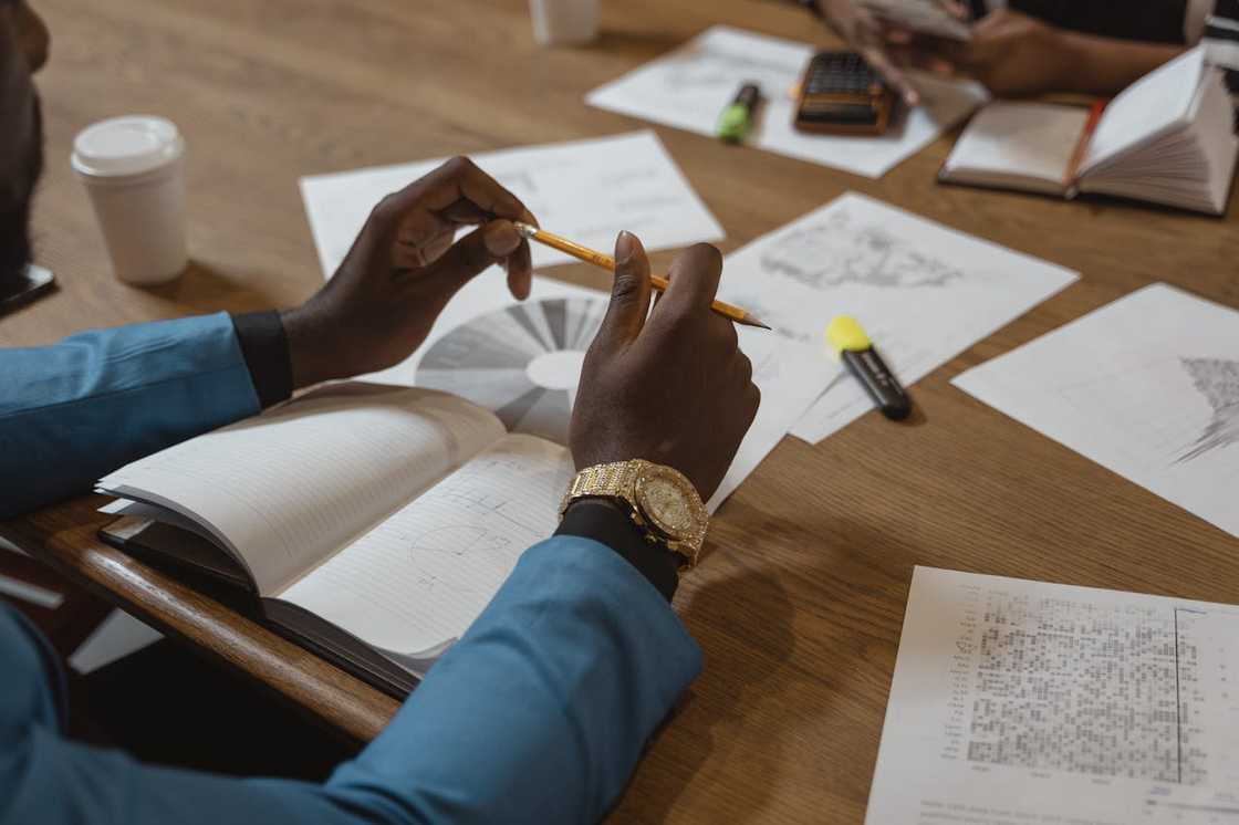 A man holding a pencil above an open notebook, during a focused discussion.