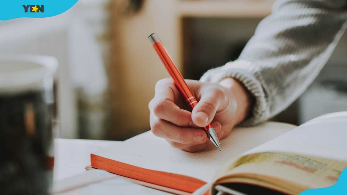 A person holding an orange pen