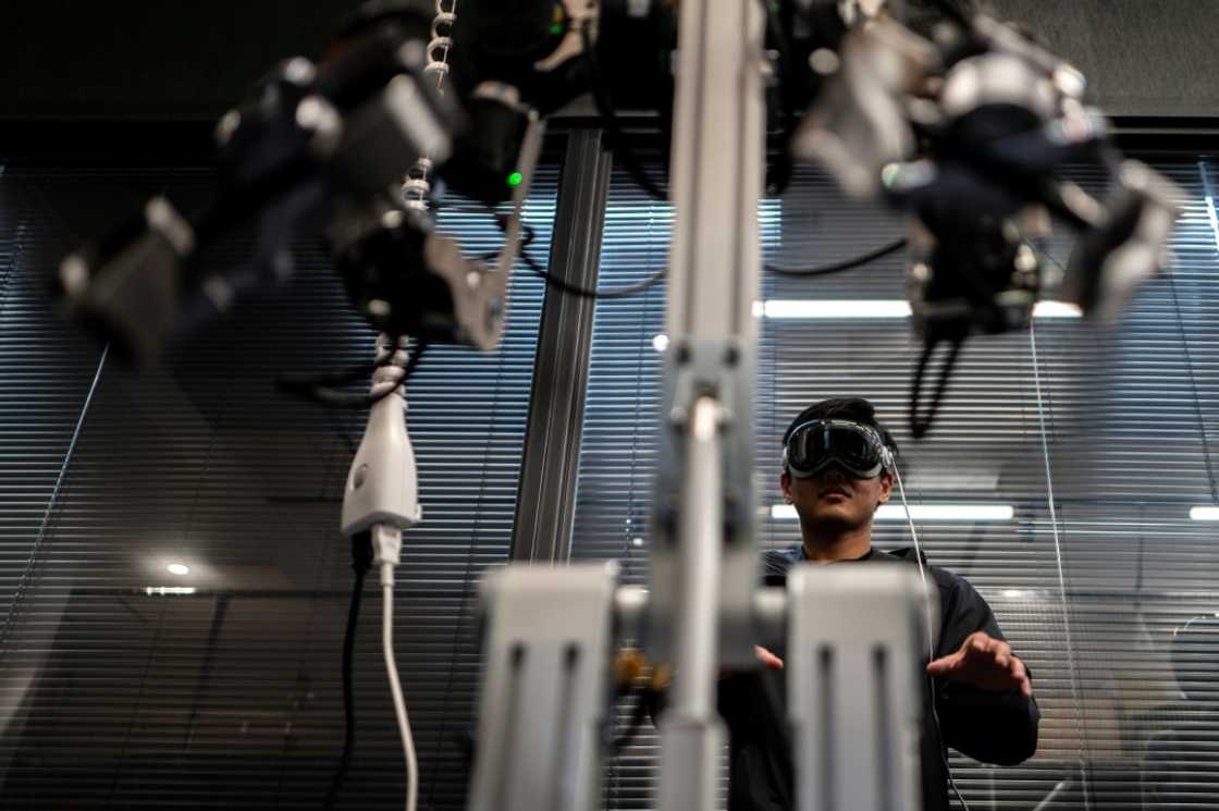 An engineer (back), of company Enactic, tele-operating with a VR headset and a robotic arm in the company's office in Tokyo An engineer (back), of company Enactic, tele-operating with a VR headset and a robotic arm in the company's office in Tokyo