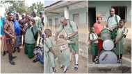 Man donates bags, drums to school kids, dresses like them, kneels and raises up his hands in photo