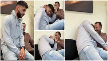 Grown-up man pranks dad by sitting on his lap, his father pushes him away