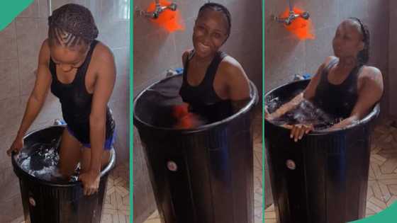 Lady dips herself in a big drum of cold water, swims in it like a swimming pool